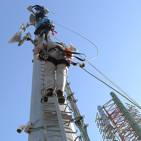 Operatori intenti al lavoro su torre per ponti radio